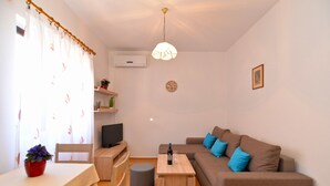 Una sala de estar acogedora con un sofá marrón, una mesa de centro de madera, un televisor y un comedor con mesa y sillas.