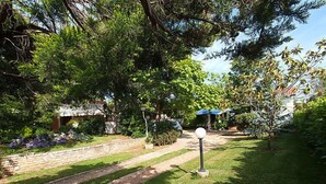 A garden pathway with stone borders, surrounded by lush greenery and trees. - Apartment 1770 (Kanfanar)