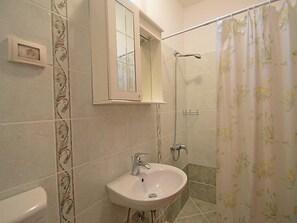 A bathroom with a sink, mirror, shower, and toilet. - Apartment 1770 (Kanfanar)