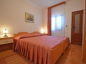 A bedroom with a large bed, two bedside tables with lamps, a door, and a window with curtains. - Apartment 1770 (Kanfanar)