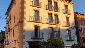 A corner building with a ground-floor restaurant, multiple balconies, and a visible entrance. - Hotel Terminus Puigcerdà (Puigcerda)