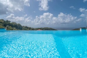 A clear blue pool with a view of a tropical landscape and distant hills.