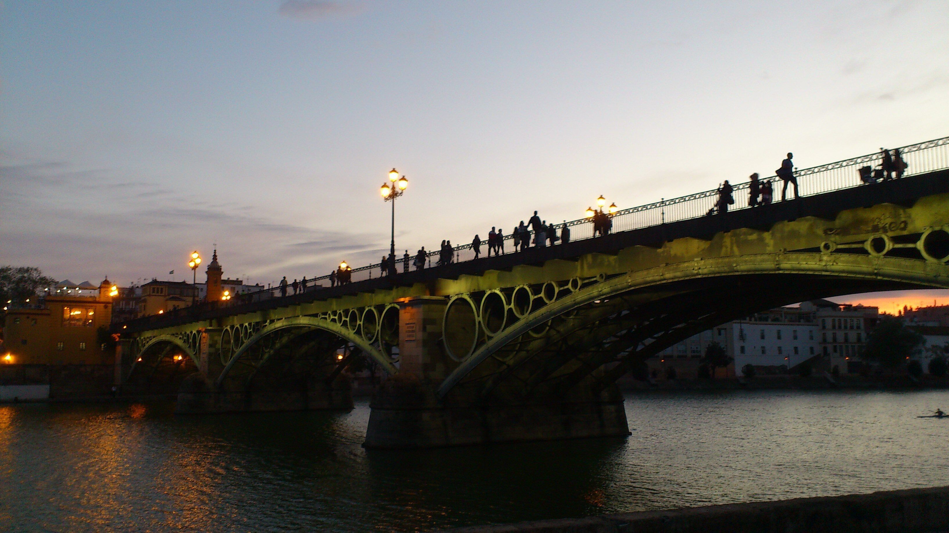 Un pont à arches multiples enjambant une étendue d’eau, sur lequel des personnes se promènent.
