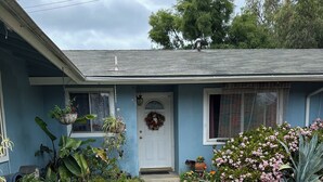 A house with a front porch, a brick pathway, and various plants and flowers. - Eva's Place  (Oak View)