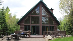 Een blokhut met een ruim terras, zitplaatsen buiten en een barbecue.