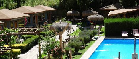 Alberca al aire libre, sombrillas en la alberca y camastros