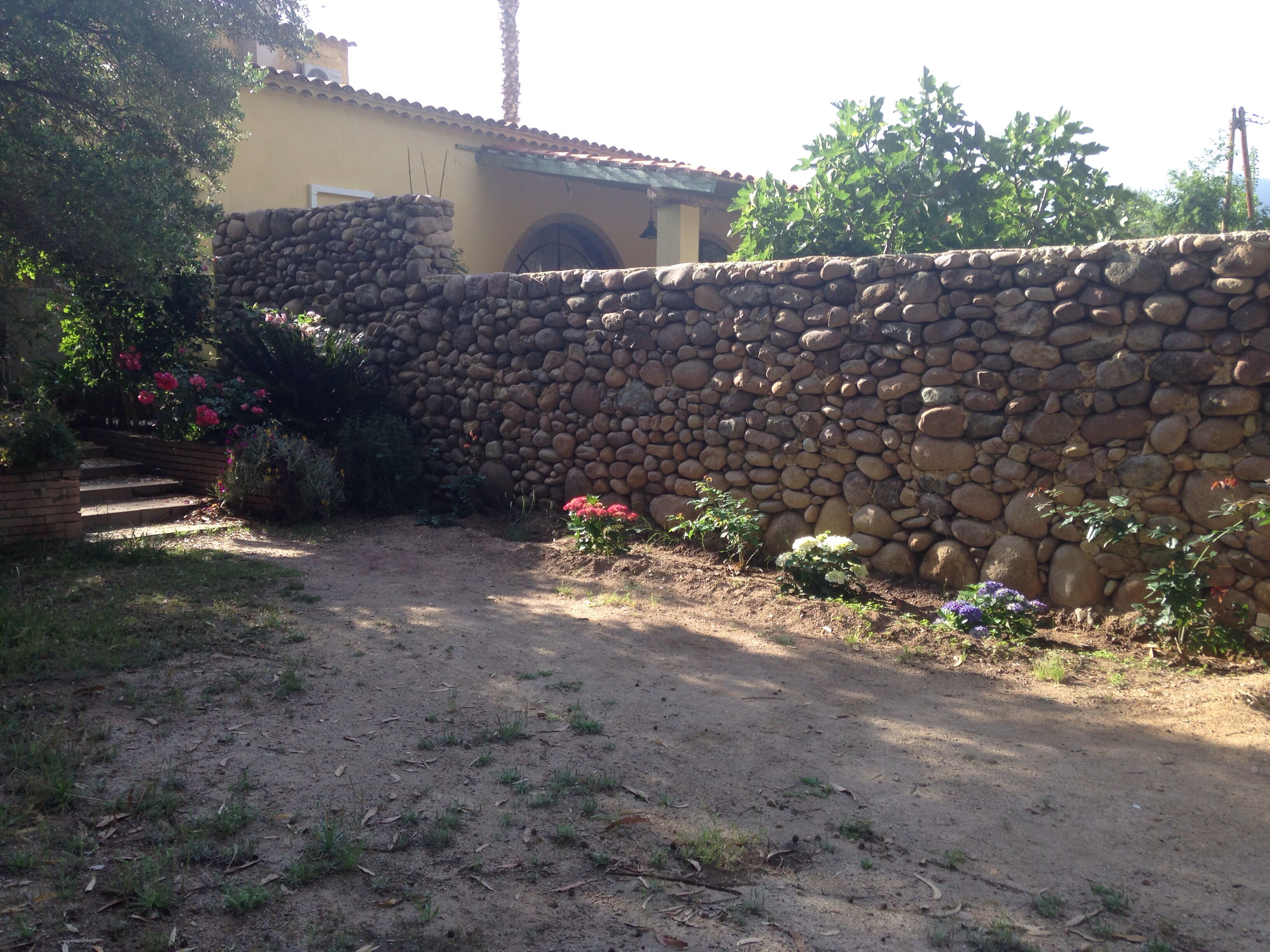 A stone wall with a rustic, stone building in the background.