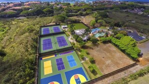 Luchtbeeld van een sportcomplex met meerdere tennisbanen en een zwembad.