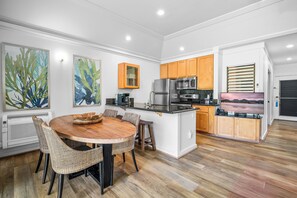A modern kitchen with a dining area, featuring a round wooden table, wicker chairs, and a built-in microwave. - Rare find w/ 2 AC, 2 min walk to beach, Remodeled #151, ground floor!  (Koloa)