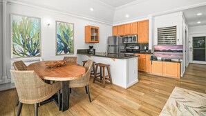 A modern kitchen with wooden cabinets, a central island, and a dining area with wicker chairs.