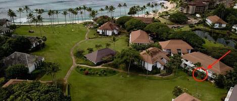 An aerial view of a coastal residential area with houses, a golf course, and a beach.