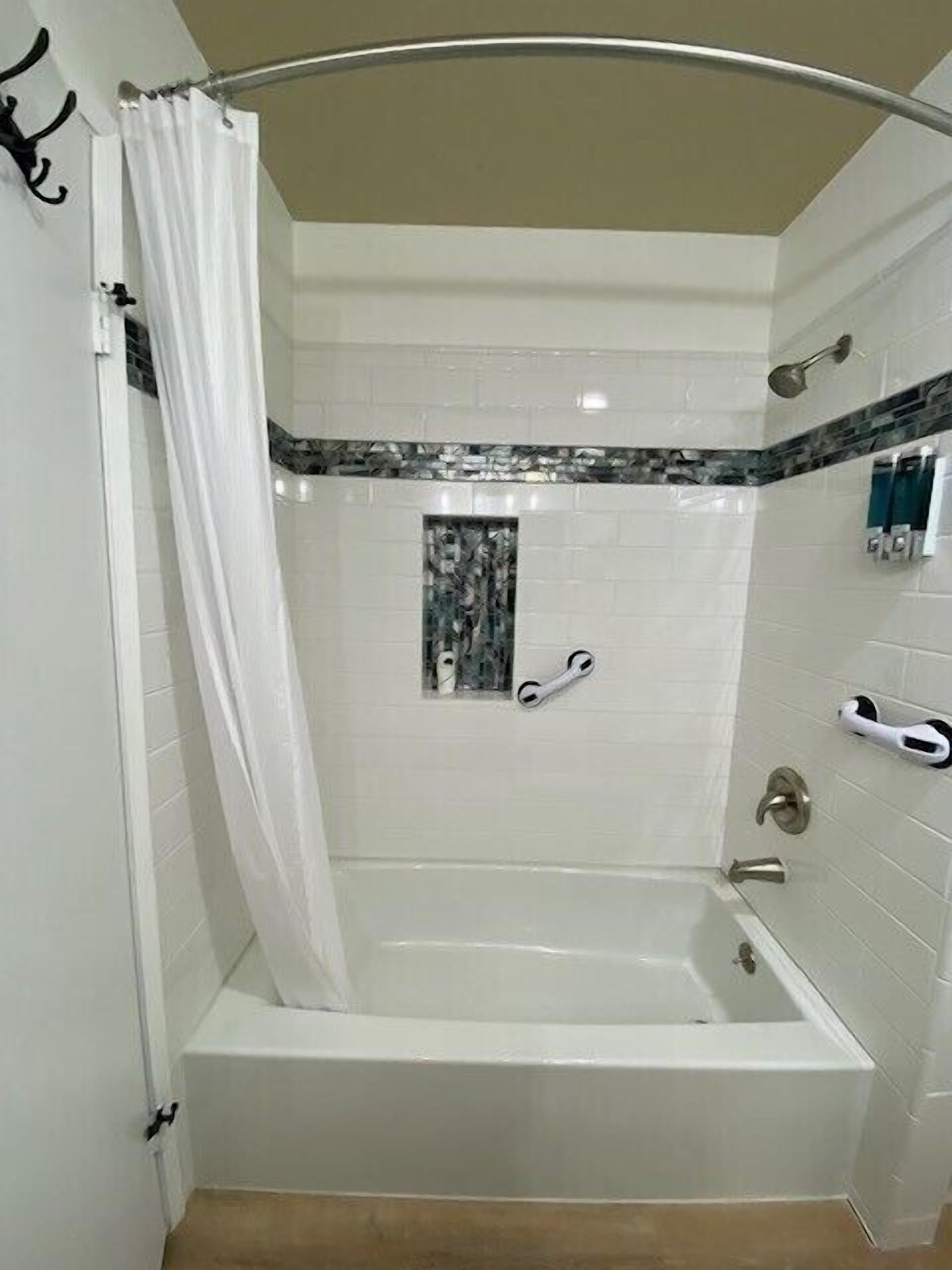 A modern bathroom with a bathtub, shower curtain, and tiled walls.