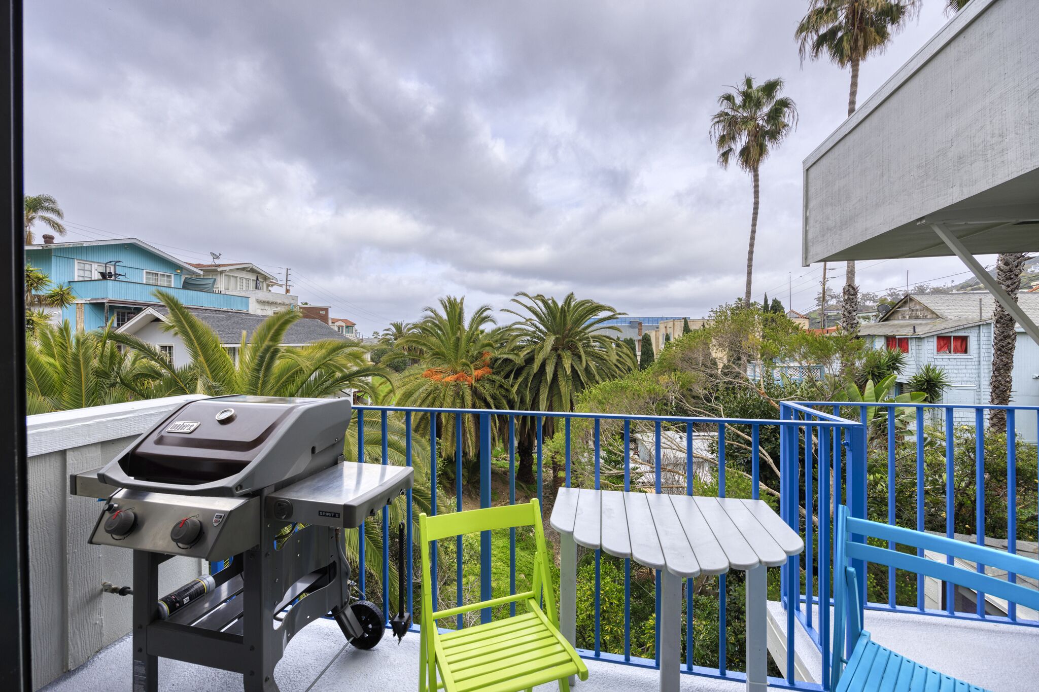 Un balcon avec un barbecue, une chaise verte et une petite table.