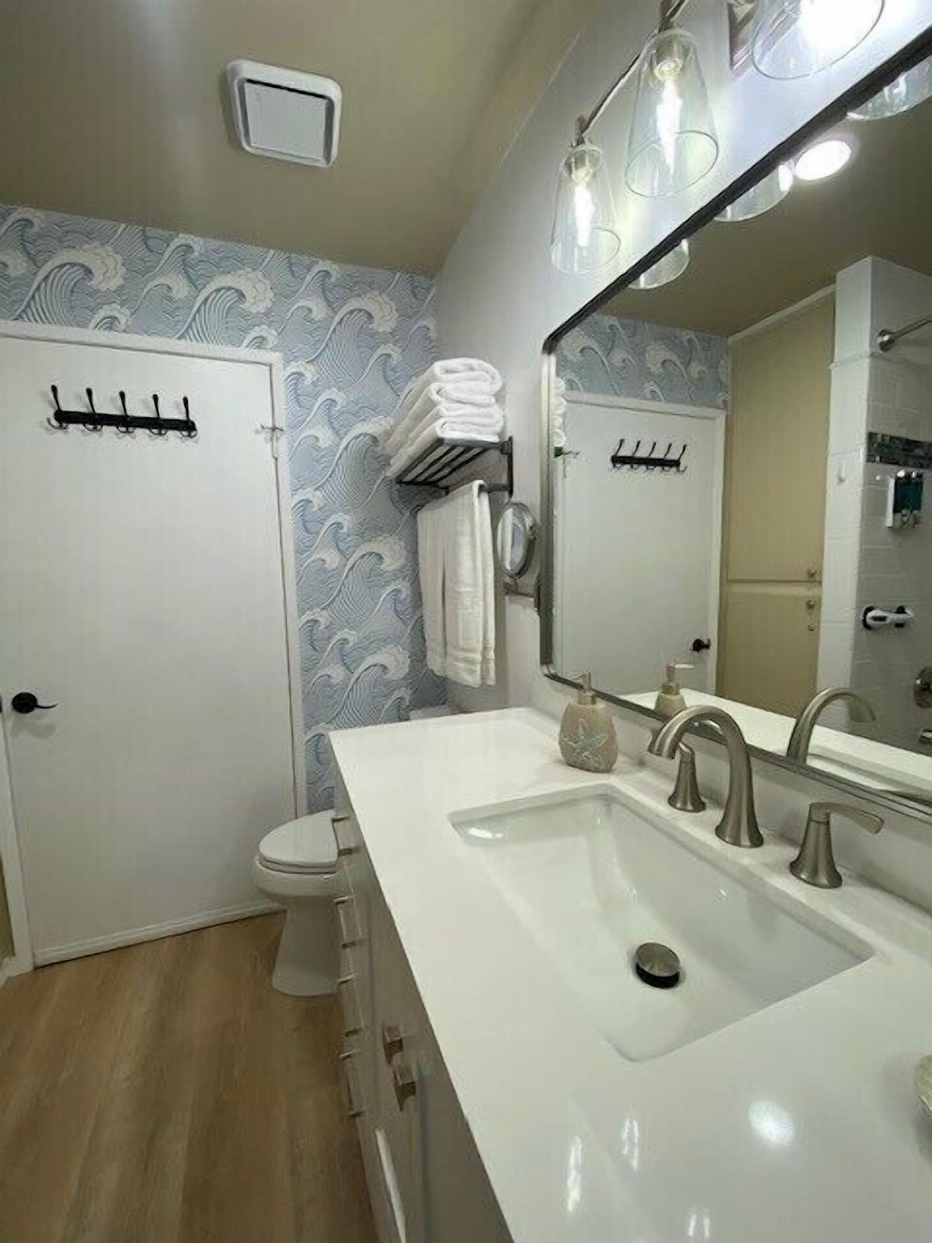 Een badkamer met een witte wastafel, een spiegel en een handdoekhouder.