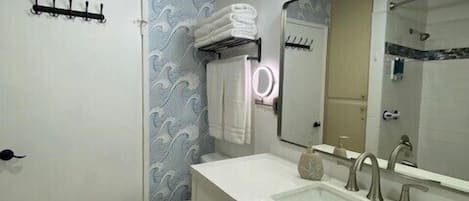 Un baño con inodoro blanco, lavamanos con espejo y un perchero para toallas.