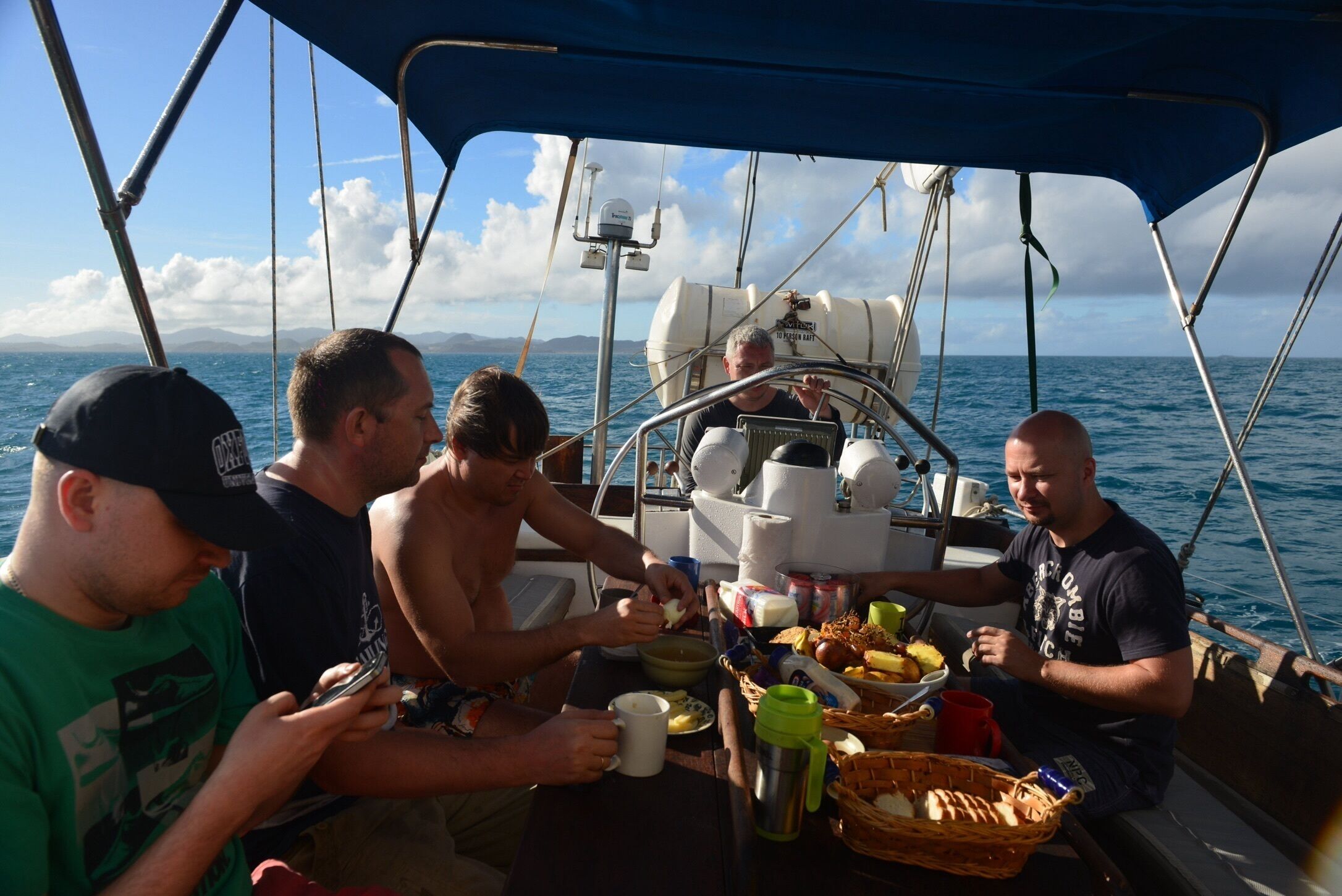A group of people dining on a boat with a view of the sea and distant land.