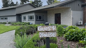 Ein Gästehaus mit einem Schild, umgeben von gepflegten Gärten und einem Weg zum Eingang.