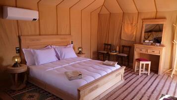 A tent-style bedroom with a wooden bed, bedside lamps, a small desk, and a mirror.