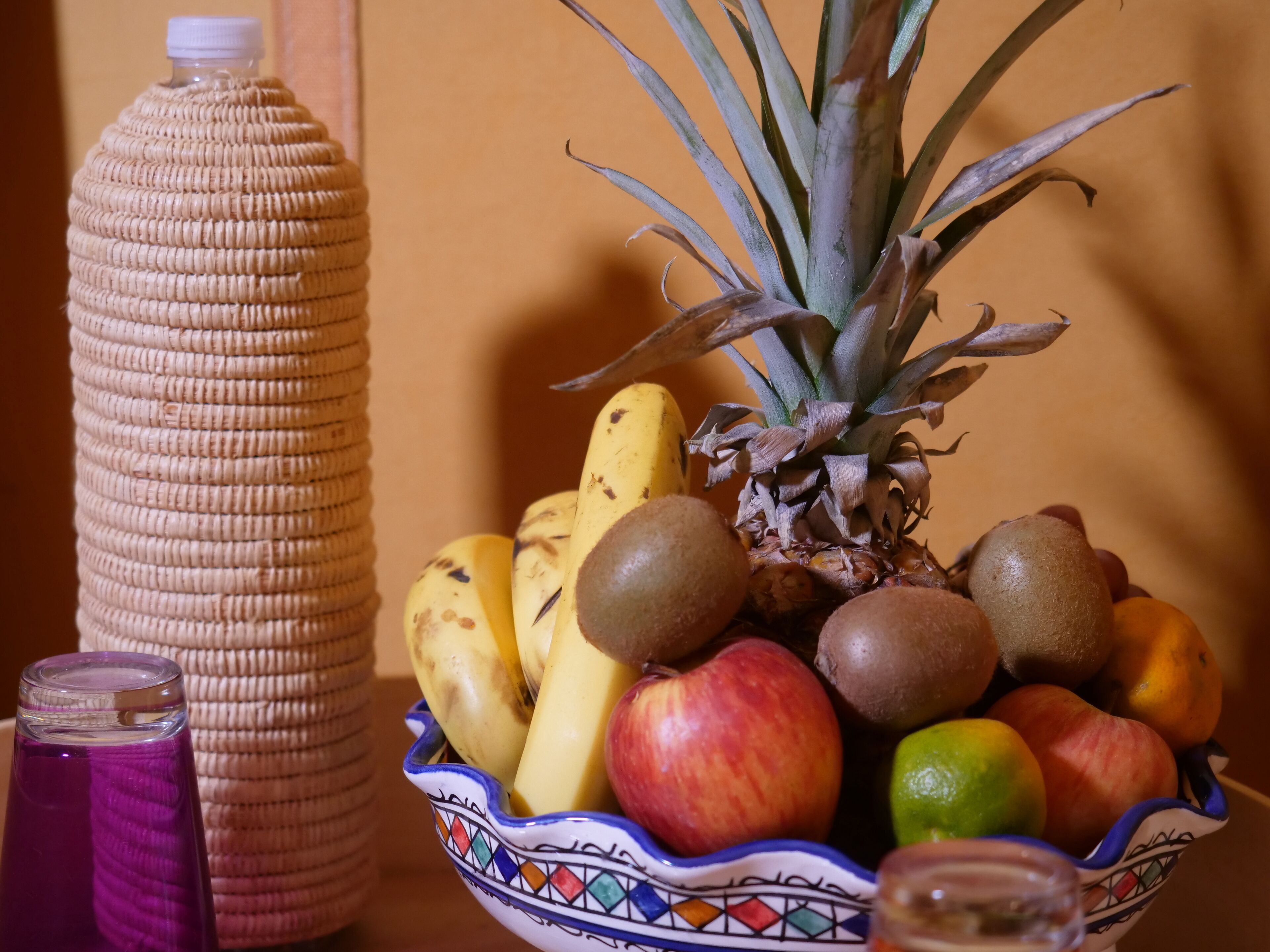 Een fruitschaal met ananas, bananen, kippenfruit, appels en sinaasappels.