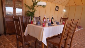 Una mesa de comedor con sillas, una planta en maceta y diversos utensilios de mesa.