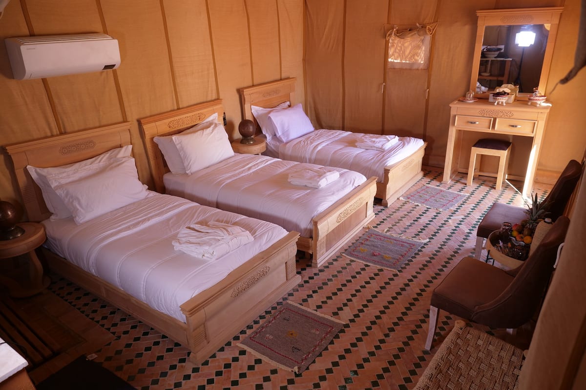 Ein Hotelzimmer mit zwei Holzbetten, einem Schreibtisch aus Holz, einem Stuhl und einem Spiegel.