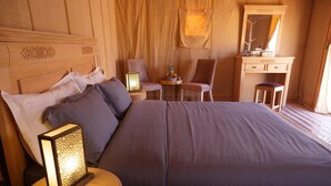 Un dormitorio ordenado con una cama grande, dos mesitas de noche con lámparas, una silla, un escritorio y un espejo.