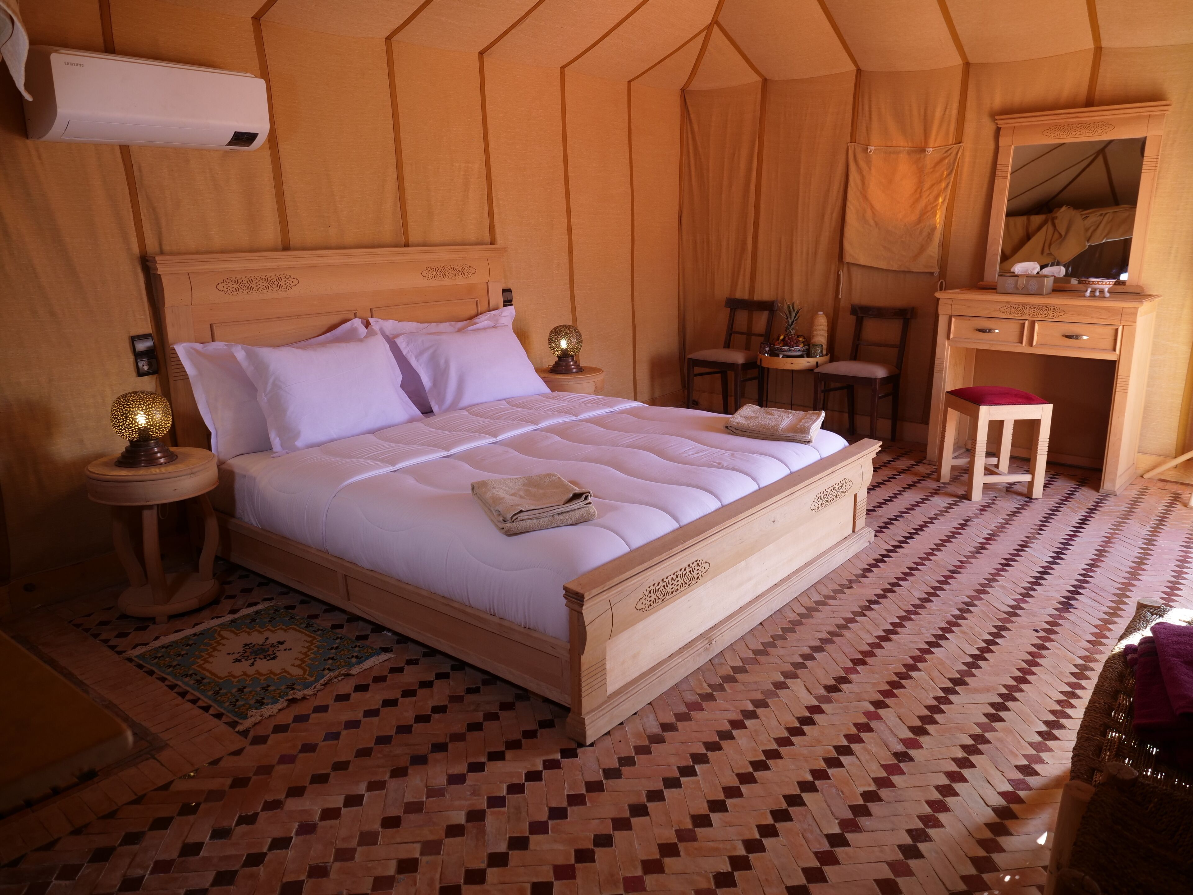 Un dormitorio amplio con una cama grande, cabecera de madera y un escritorio pequeño con espejo.