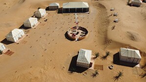Vista aérea de un resort en el desierto con varias tiendas de campaña y una zona de estar circular central.