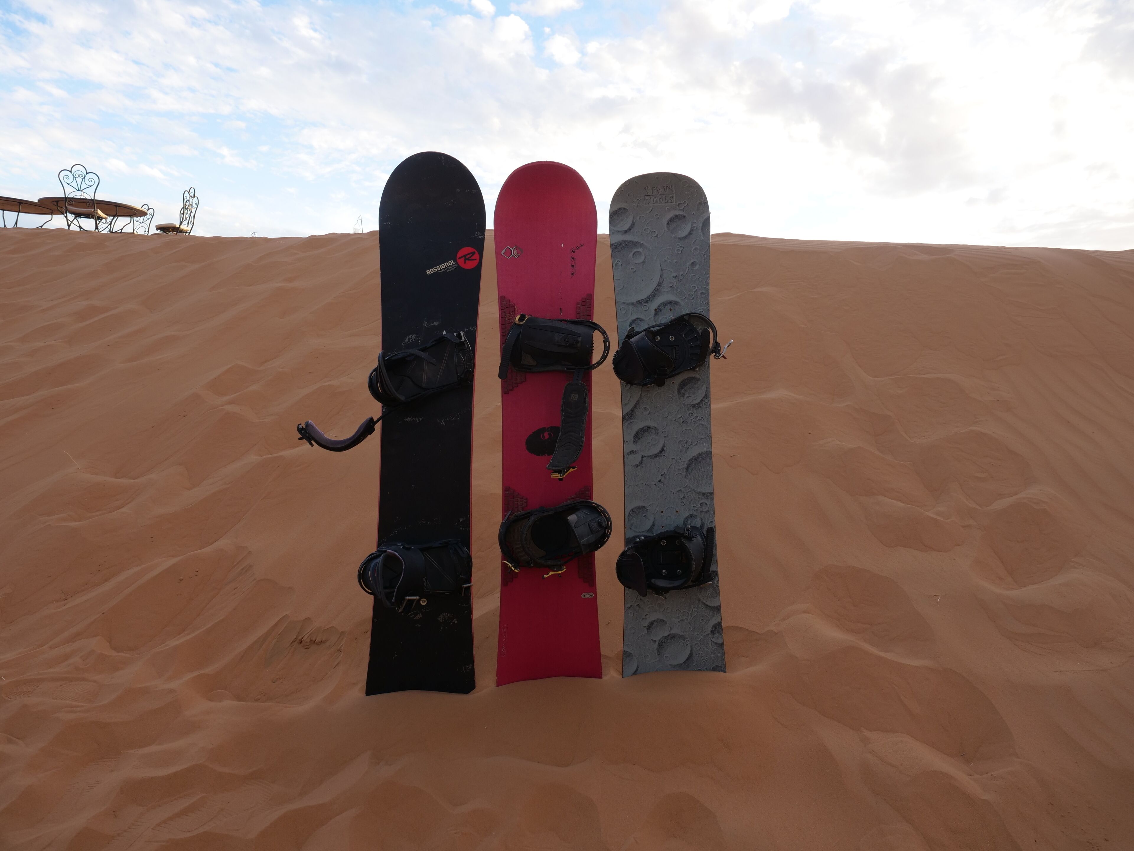 Three snowboards standing upright in a desert.