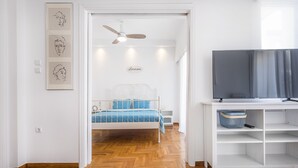 A bedroom with a bed, a ceiling fan, a TV, and a white wardrobe. - Acropolis unique view (Athina)
