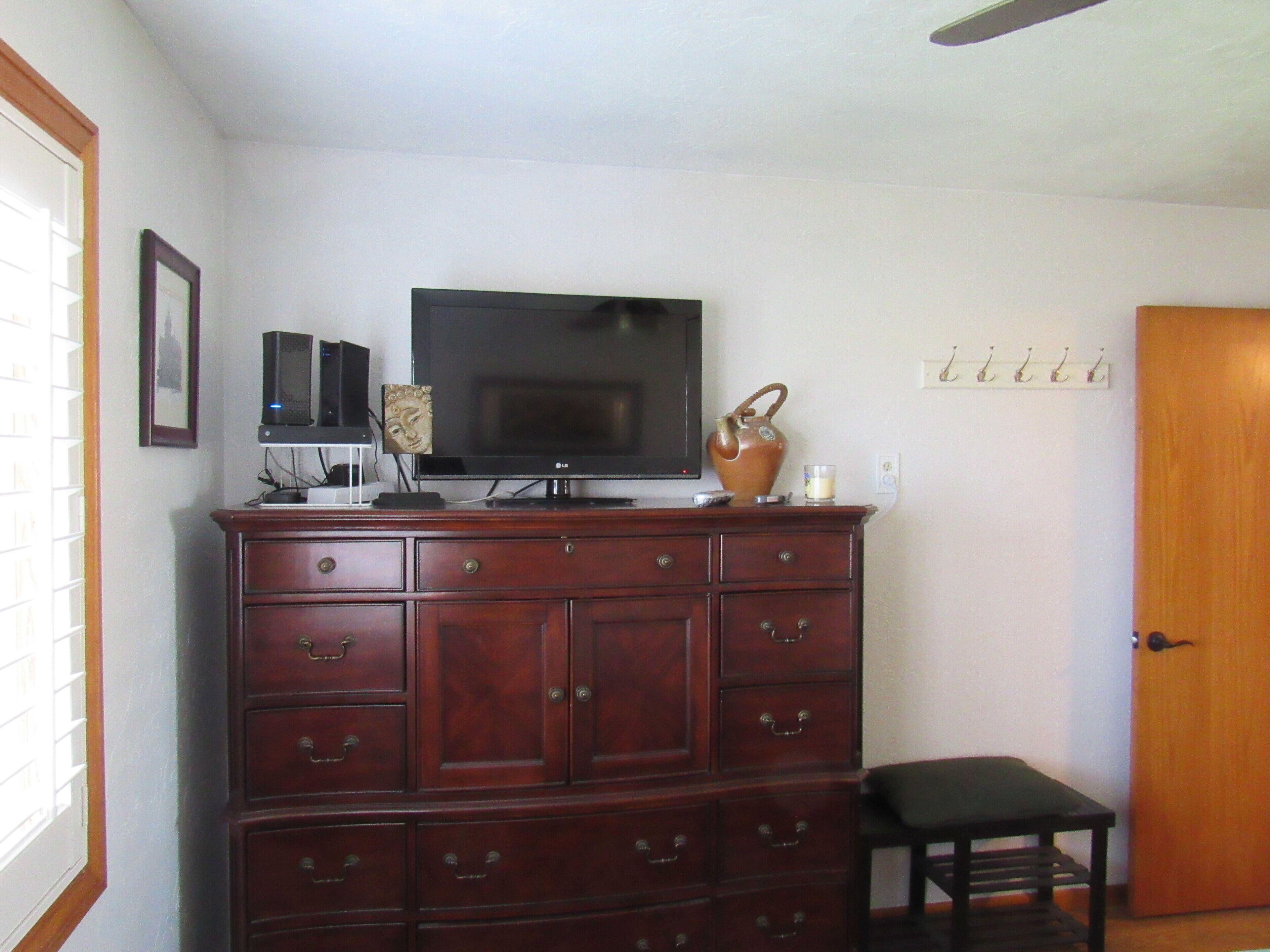 A room with a TV on a wooden cabinet, a small table, and a door.
