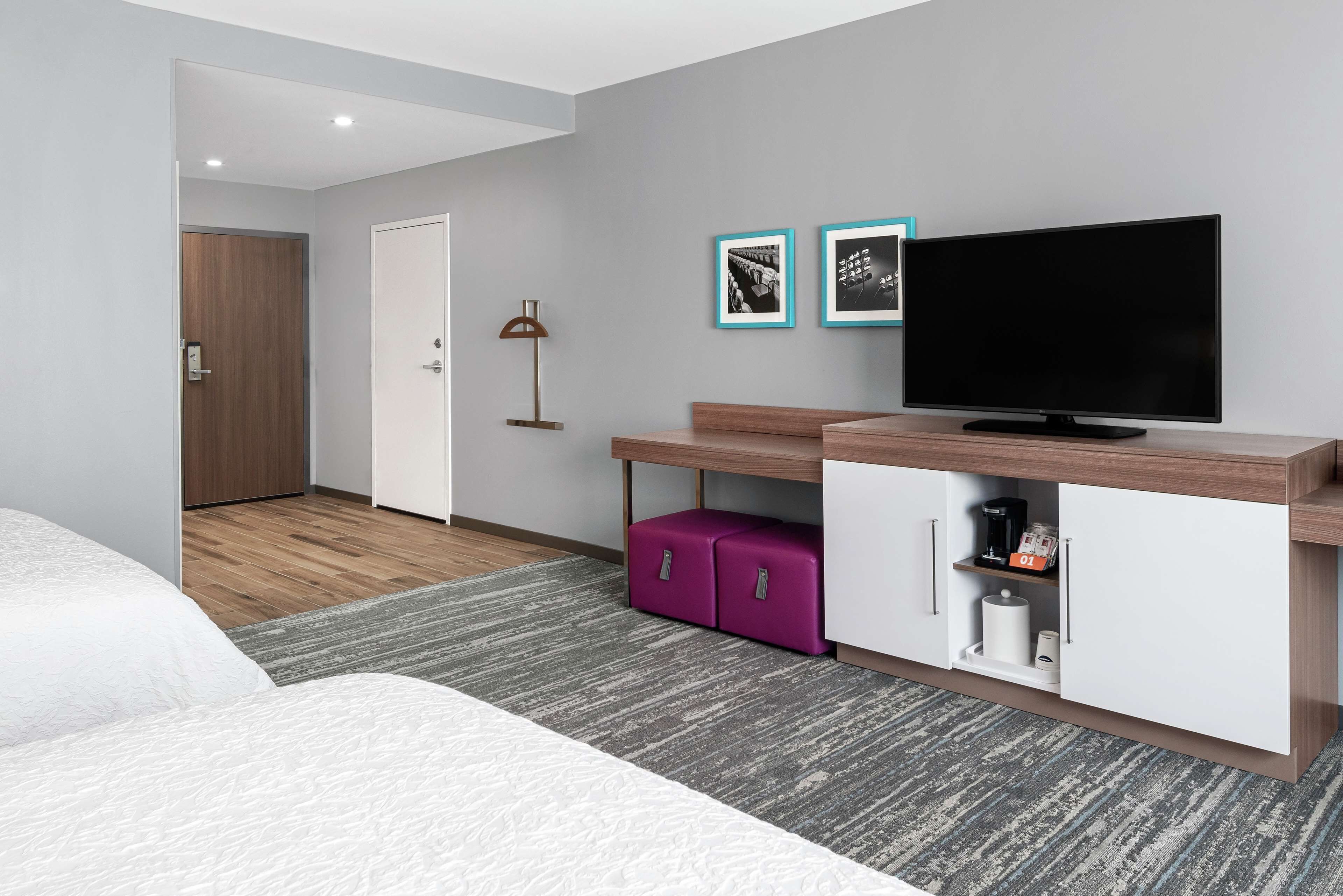 A hotel room with a bed, a TV, a desk, and a wardrobe.