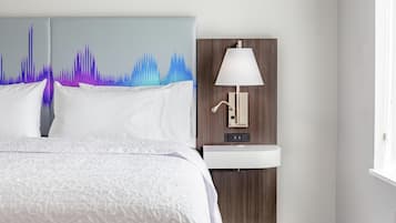 Una habitación de hotel con una cama, una lámpara de pared y un lavabo.