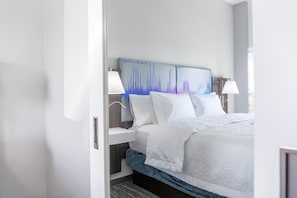 Ein Hotelzimmer mit Bett, Nachttischlampen, einem Nachttisch und einem Wandbild.