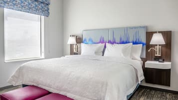 A hotel room with a large bed, two bedside lamps, a wall-mounted clock, and a window with a view.