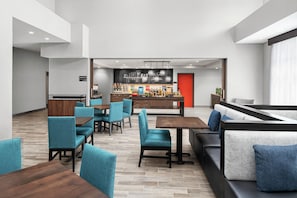 Un moderno vestíbulo de hotel con zonas de estar, una barra de desayuno y una estación de café.