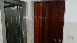 A hallway with a metallic elevator and a wooden door. - B&B Anter (Monopoli)