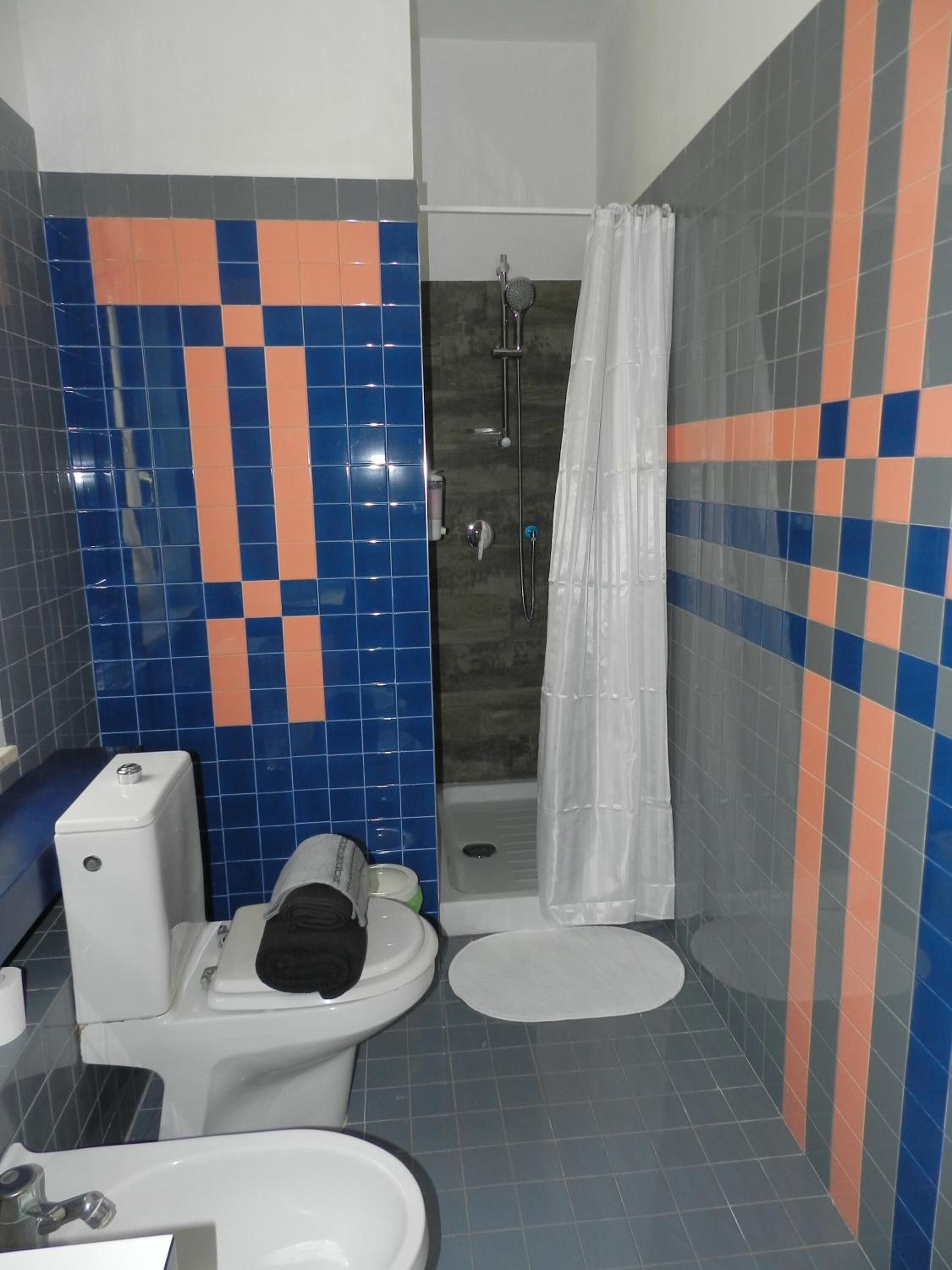 A bathroom with a toilet, sink, and shower area.