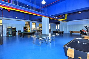 Ein großzügiger Innenbereich mit Tischtennisplatte, Billardtischen und verschiedenen Spielautomaten.