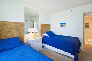 Ein Schlafzimmer mit zwei Betten, einem Nachttisch, einer Lampe und einem gerahmten Bild an der Wand.