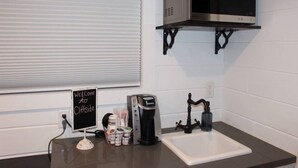 A kitchenette with a coffee maker, a microwave, and a sink. - Mini farmhouse style container Homes #3 (Orderville)
