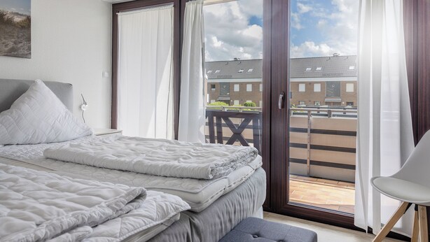 Ein Schlafzimmer mit einem Bett, einer Bank und einem Stuhl.