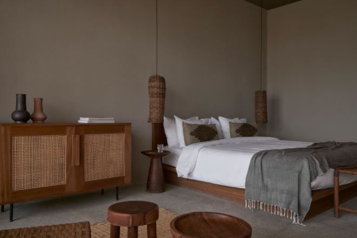 A bedroom with a wooden bed, a rattan cabinet, and a small round table.