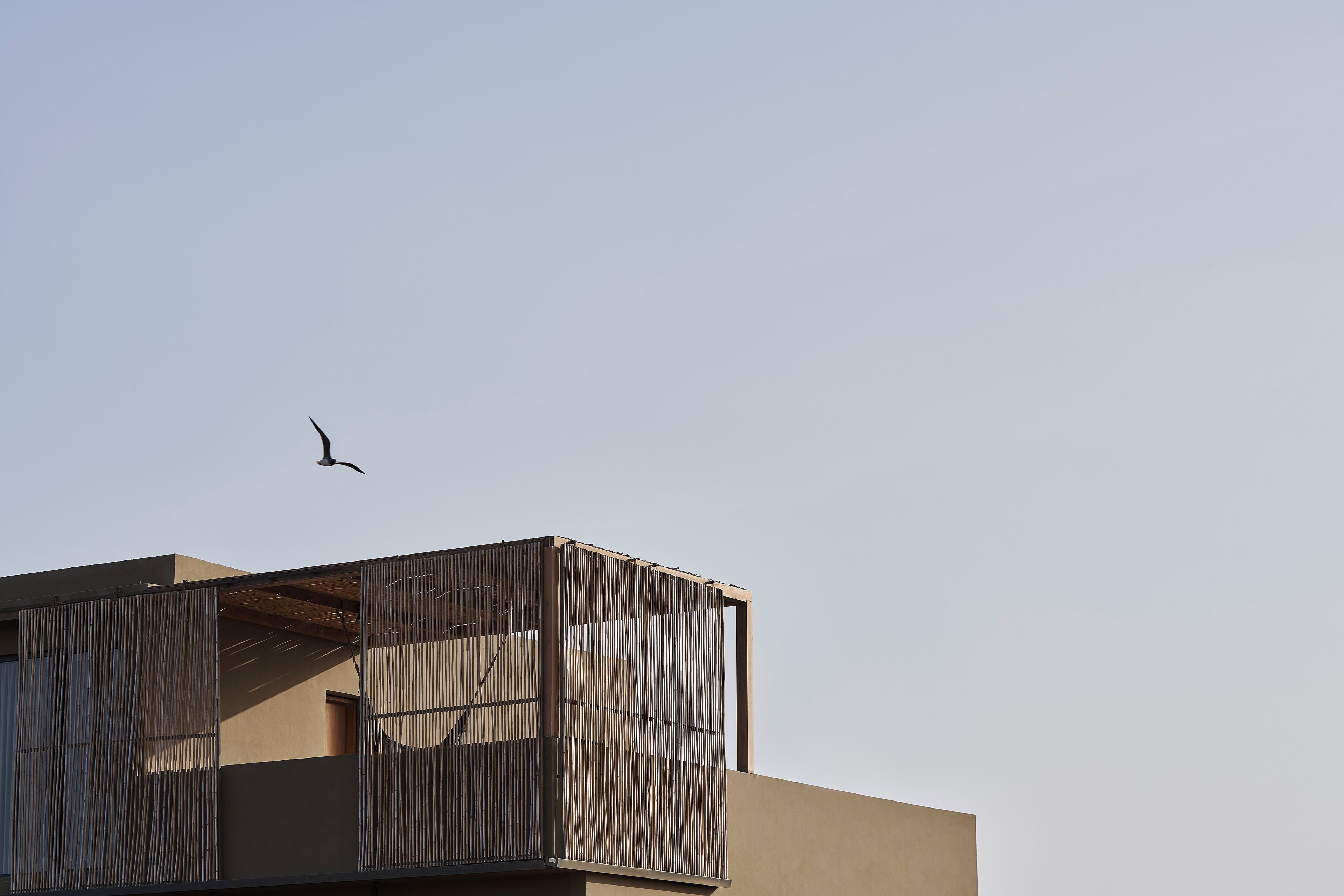 A building with a balcony and a bird flying in the sky.