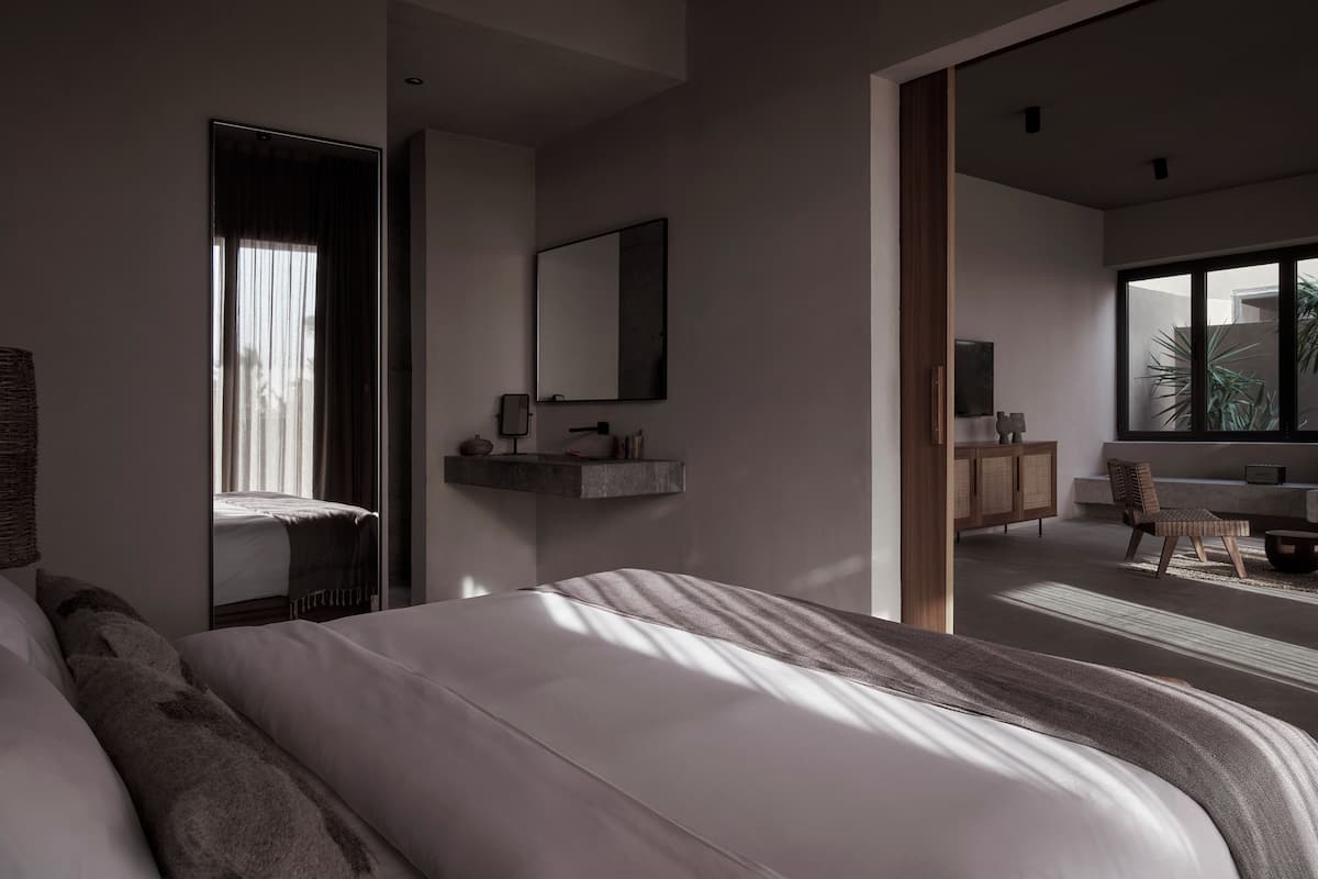 Un dormitorio moderno con una cama grande, una mesita de noche, un espejo y vistas a un balcón.