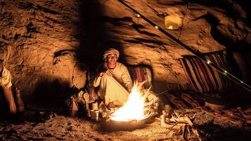 A cave interior with a fire, stone walls, and a striped fabric hanging.