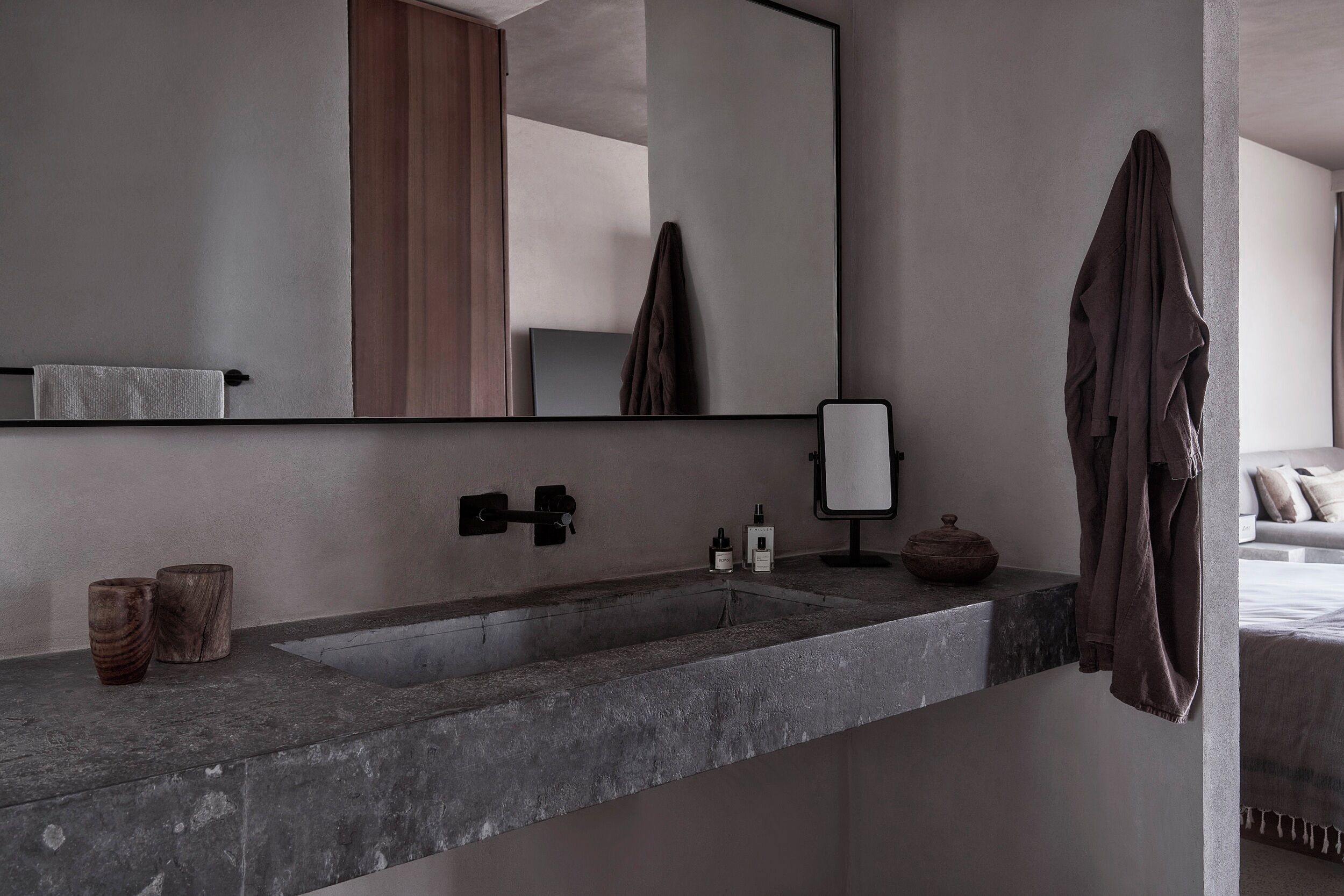 A modern bathroom with a large mirror, a sink, and a towel rack.