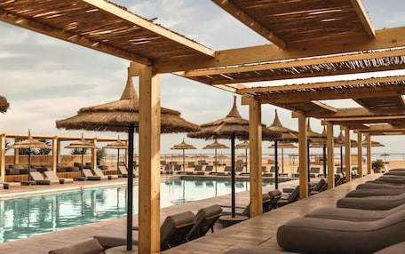 A poolside area with lounge chairs and thatched umbrellas.