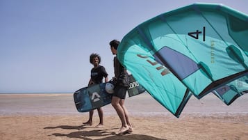 Two people on a beach holding a kiteboard.