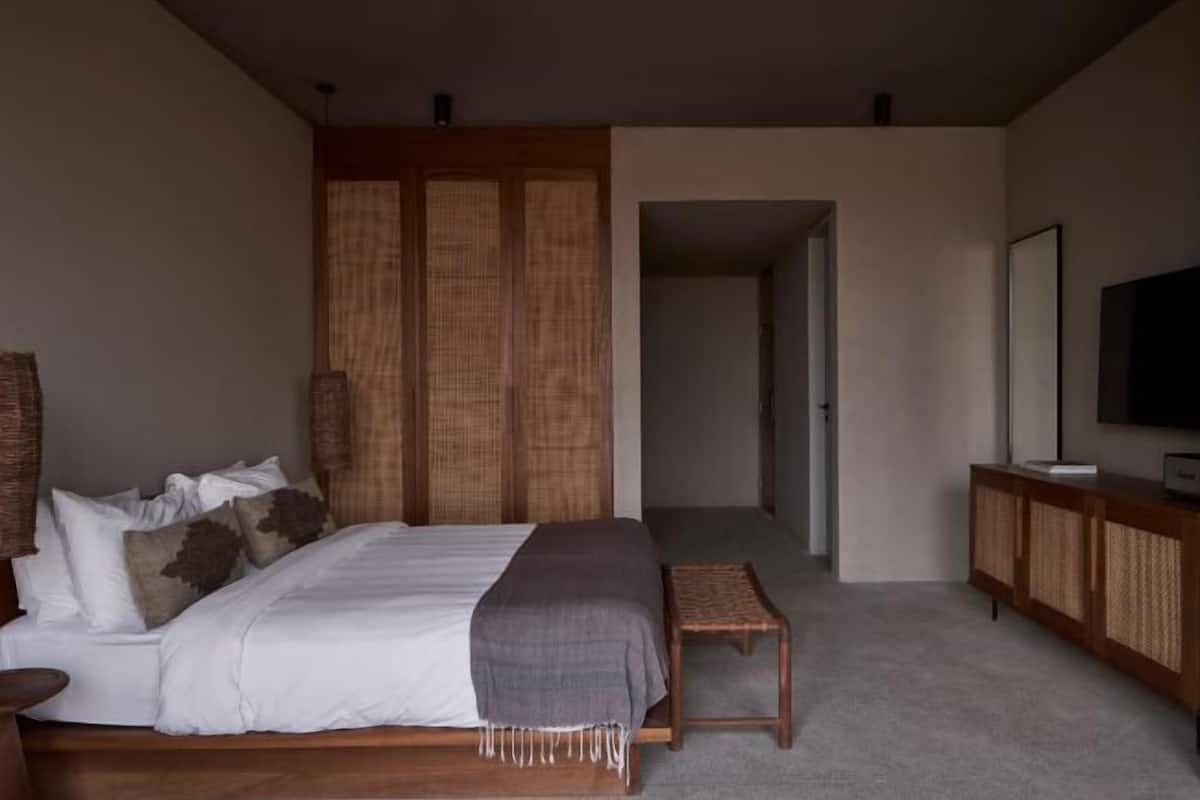Un dormitorio con cama, un armario de madera, un televisor y una pequeña mesa.